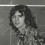 A young man with long hair and a shirt on.