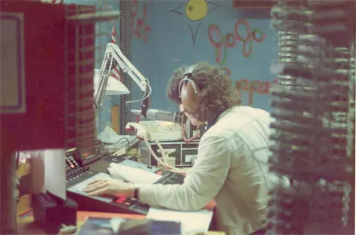 A person sitting at a desk in front of a microphone.