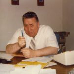 A man sitting at a desk with papers and pens.