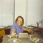 A woman sitting at the stove in her kitchen.