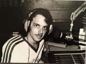 A man with headphones on in front of some other people.